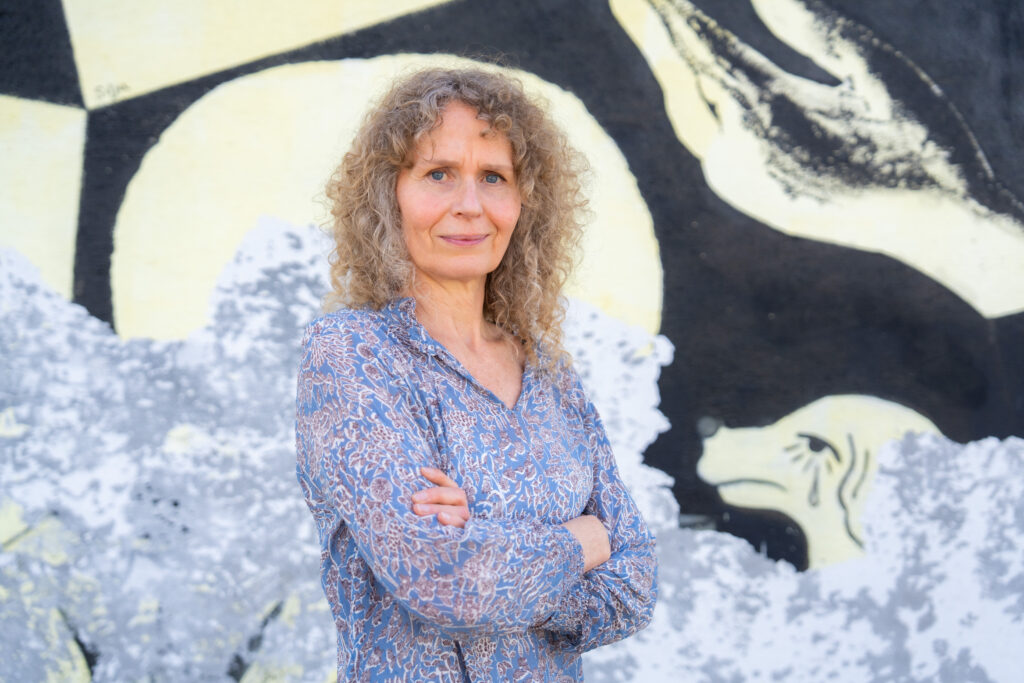 Hanne Cecilie Widnes står med korslagte armer foran en grafittivegg.
